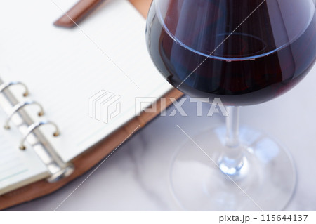 赤ワインを飲みながら、リング式のシステム手帳に日記をつけているイメージ写真 115644137