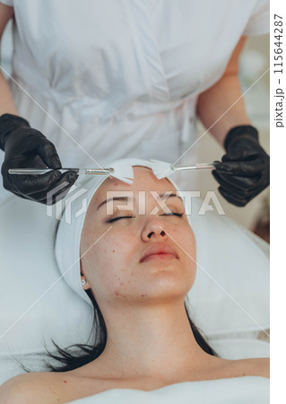 A girl at a cosmetologist does cosmetic procedures. Skin cleansing 115644287