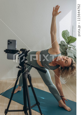 A 50-year-old woman doing online yoga at home 115644762