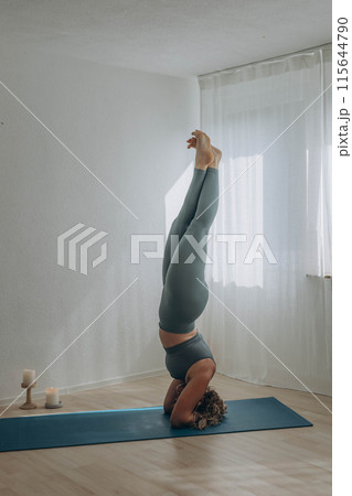 A 50-year-old woman does yoga at home 115644790