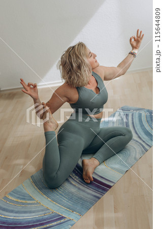 A 50-year-old woman does yoga at home 115644809
