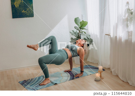 A 50-year-old woman doing online yoga at home 115644810