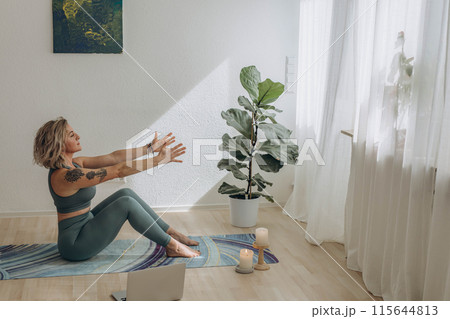 A 50-year-old woman doing online yoga at home 115644813