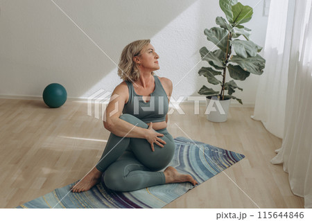 A 50-year-old woman does yoga at home A 50-year-old woman does yoga at home 115644846