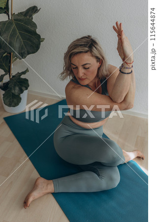 A 50-year-old woman does yoga at home 115644874