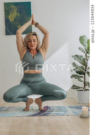 A 50-year-old woman doing online yoga at home 115644934