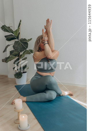 A 50-year-old woman does yoga at home 115644939