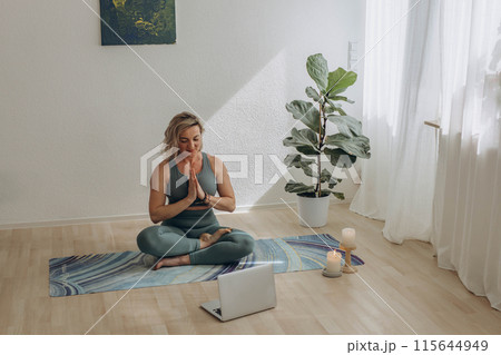 A 50-year-old woman doing online yoga at home 115644949