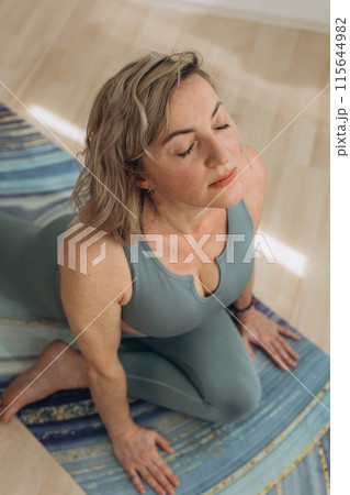A 50-year-old woman does yoga at home A 50-year-old woman does yoga at home 115644982