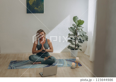 A 50-year-old woman doing online yoga at home 115644986