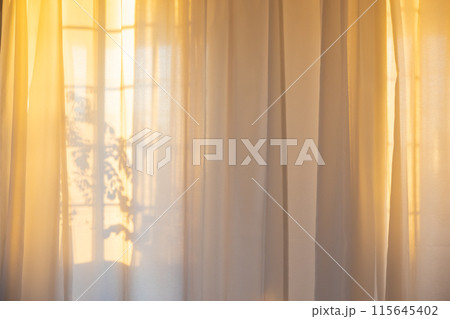 カーテンから差し込む夕日 115645402