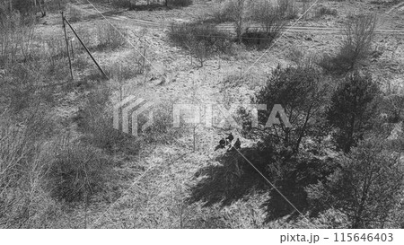 Men Dressed As US American Soldiers Of USA Infantry Of World War II open fire shooting mortar In spring Autumn Day. Soldiers shots mortar during battle In dry grass. Aerial view elevated shot 115646403