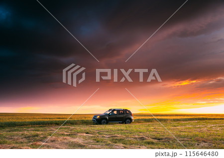 AWD 4WD SUV green car in summer meadow landscape in summer field countryside landscape. Sunset sky background AWD 4WD SUV green car in summer meadow landscape in summer field countryside landscape. Sunset sky background 115646480