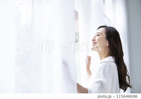 カーテンを開ける若い女性 115646696