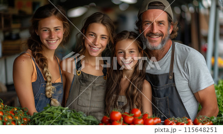 A family of four smiling and posing for the camera at their farm stand, surrounded by fresh produce like tomatoes and greens. 115648251