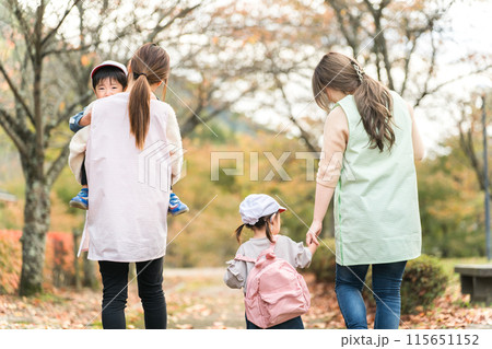 秋の公園を散歩・遠足する保育士の女性と園児(保育園・幼稚園保母) 秋の公園を散歩・遠足する保育士の女性と園児(保育園・幼稚園保母) 115651152