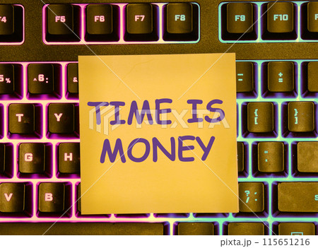 Business concept. Copy space. The words TIME IS MONEY on a yellow sticker lying on the keyboard with a colored backlight Business concept. Copy space. The words TIME IS MONEY on a yellow sticker lying on the keyboard with a colored backlight 115651216