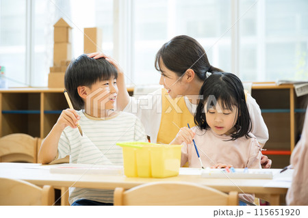 学童や放課後デイサービス等で勉強をする先生と生徒 小学生複数と見守る褒める先生と笑顔 学童や放課後デイサービス等で勉強をする先生と生徒 小学生複数と見守る褒める先生と笑顔 115651920