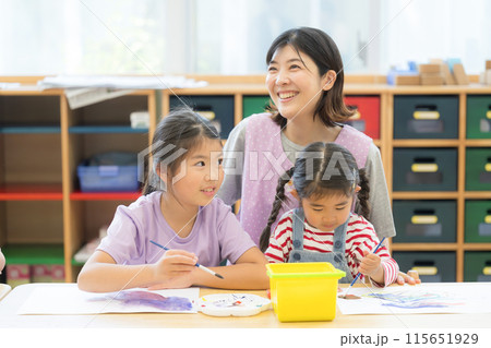 学童や放課後デイサービス等で勉強をする先生と生徒 小学生複数と見守る先生 学童や放課後デイサービス等で勉強をする先生と生徒 小学生複数と見守る先生 115651929