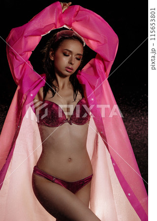 A woman in a pink raincoat is standing in the rain 115653801
