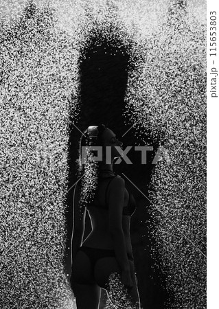 A woman stands in the rain, her body partially obscured by the spray of water A woman stands in the rain, her body partially obscured by the spray of water 115653803