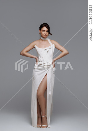 Woman in a white wedding dress on a gray background. Woman in a white wedding dress on a gray background. 115653812
