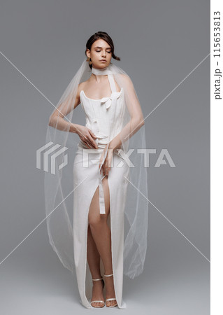Woman in a white wedding dress on a gray background. Woman in a white wedding dress on a gray background. 115653813