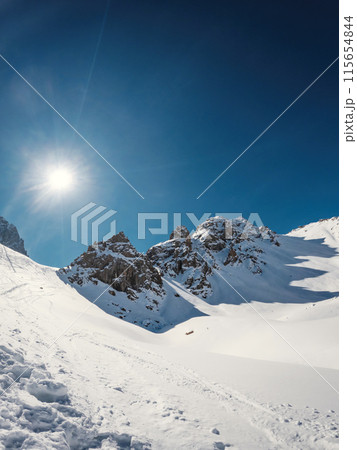 Snow-capped high mountain pass: Three majestic rocky peaks, kissed by the winter sun, casting captivating shadows. Plenty of copy space in the vertical frame. Snow-capped high mountain pass: Three majestic rocky peaks, kissed by the winter sun, casting captivating shadows. Plenty of copy space in the vertical frame. 115654844