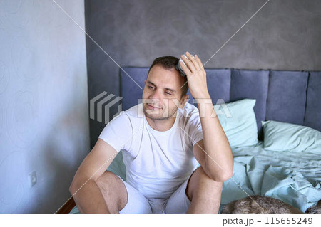 a man massages his head with an electric massager for hair growth 115655249