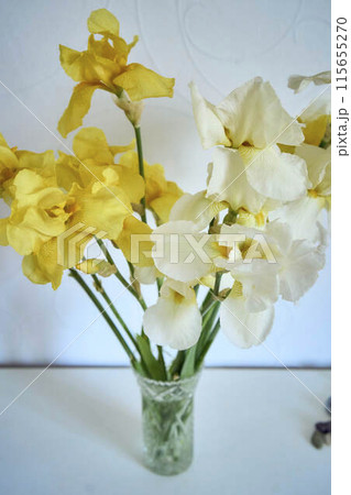 a  bouquet of yellow and white irises in a crystal vase in the interior 115655270