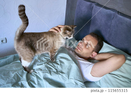 a young man sleeping with a cat on his chest, morning routine 115655315