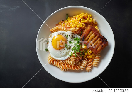Tasty twisty pasta with fried egg, crispy ham, and sweet corn in a white bowl 115655389