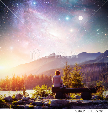 Lake Strbske pleso in High Tatras mountain, Slovakia, Europe. Fantastic starry sky and the milky way. The girl sits on a bench and looks into the fairy-tale sky. Courtesy of NASA 115657842