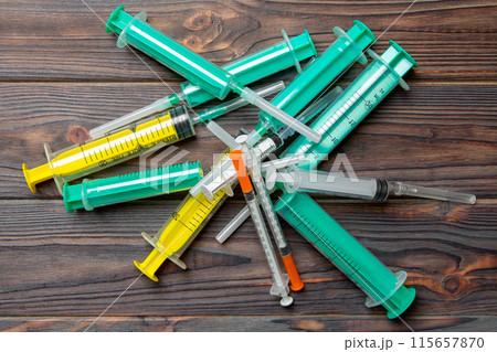 Top view of a pile of syringes and insulin syringes ready for injection at wooden background. Health care concept with copy space Top view of a pile of syringes and insulin syringes ready for injection at wooden background. Health care concept with copy space 115657870