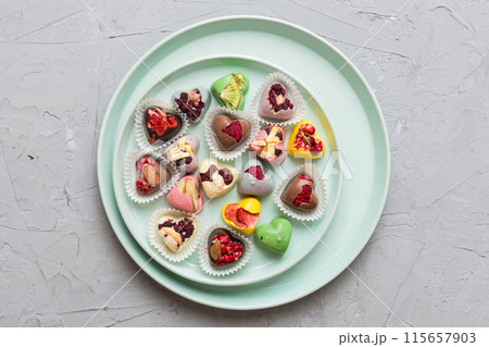 Plate with different chocolate on colored background. Assortment of fine chocolates top view vith copy space Health and obesity concept 115657903