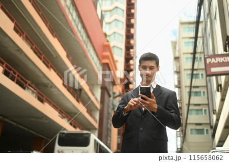 Handsome businessman using mobile phone while standing in an urban street Handsome businessman using mobile phone while standing in an urban street 115658062