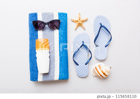 Summer holiday concept. Top view of beach towel, flip flop and sunscreen cream on table Top view with copy space for text Summer holiday concept. Top view of beach towel, flip flop and sunscreen cream on table Top view with copy space for text 115658110