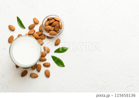 Top view of the almond milk in the glass bottle with almond nuts on the colored table. top view vith copy space 115658136