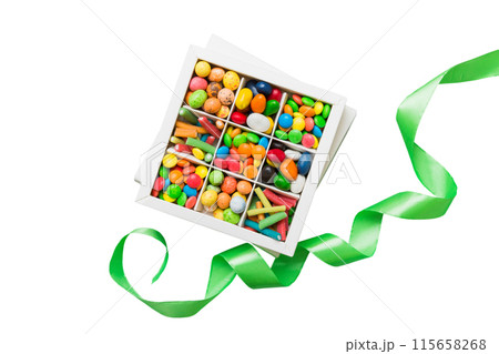 Set of different sweet candy in a paper box with a satin ribbon on a colored background. Holiday concept 115658268