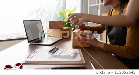 Friends Collaboration to Sell Products Online from Home Office with Laptop and Packaging Supplies 115658643