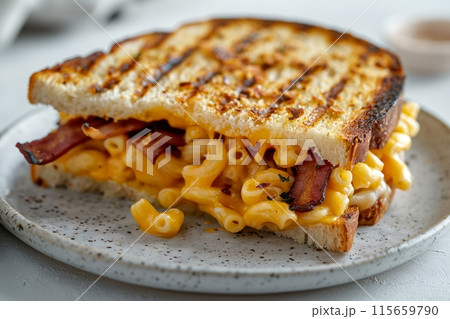 Delicious grilled cheese sandwich oozing with macaroni and bacon on a light plate 115659790