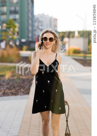 Young woman walking on city streets with while talking on her phone Young woman walking on city streets with while talking on her phone 115659840