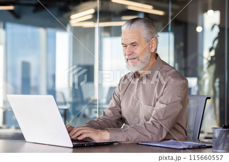 Senior man working on a laptop in a modern office, demonstrating focus and productivity. Professional work environment with glass walls and natural light. Senior man working on a laptop in a modern office, demonstrating focus and productivity. Professional work environment with glass walls and natural light. 115660557