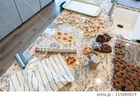 In a contemporary white kitchen, gingerbread cookie dough is skillfully rolled out, setting the stage for a delightful holiday treat. 115660625