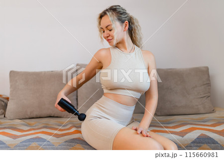 Gun shock vibration percussion massage therapy. Sporty woman practicing self-massaging your legs close up. Applying therapeutic percussive massage gun in living room at home indoors. Copy text space Gun shock vibration percussion massage therapy. Sporty woman practicing self-massaging your legs close up. Applying therapeutic percussive massage gun in living room at home indoors. Copy text space 115660981