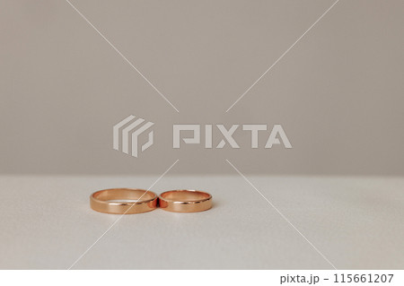 Two gold wedding rings are placed on a white table 115661207