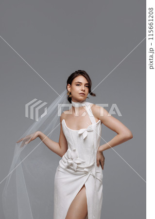 Woman in a white wedding dress on a gray background. Woman in a white wedding dress on a gray background. 115661208