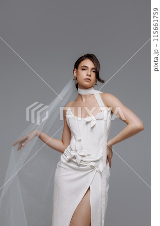 Woman in a white wedding dress on a gray background. Woman in a white wedding dress on a gray background. 115661759