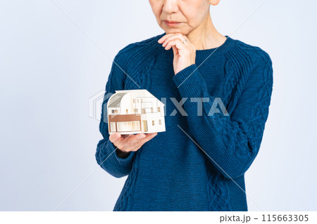 住宅模型を持って悩むシニア女性 115663305