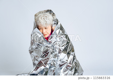 サバイバルシートに包まるシニア女性 115663316